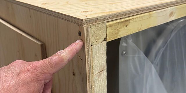 fingreer pointing at screw in top left corner of the crate.