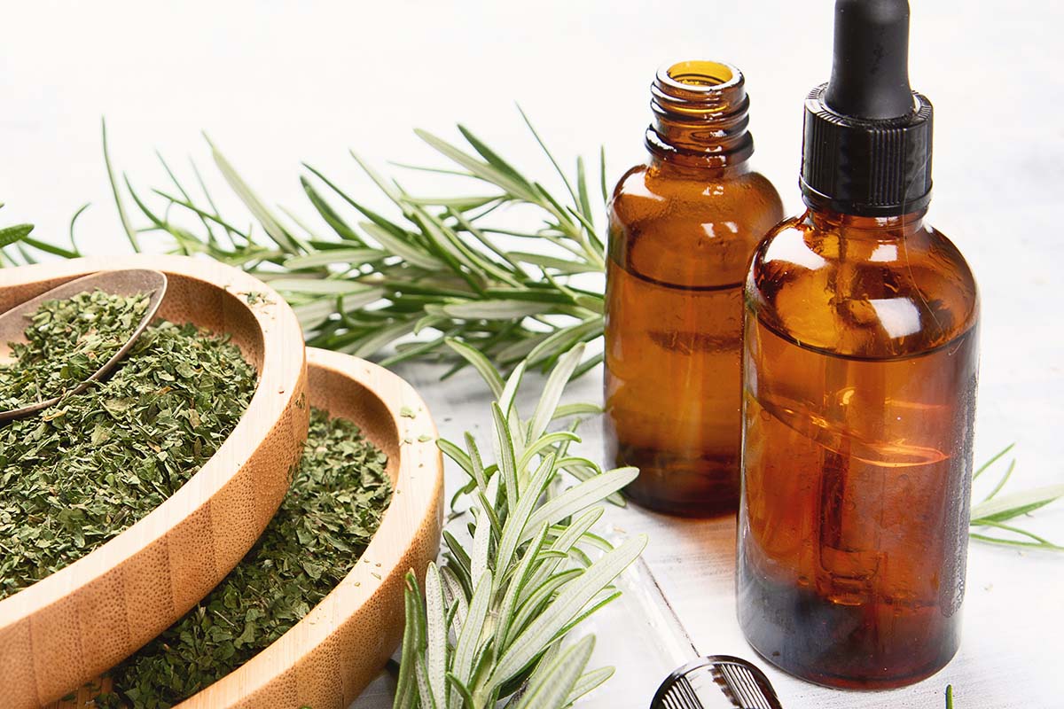 Ground rosemary next to a bottle of rosemary oil